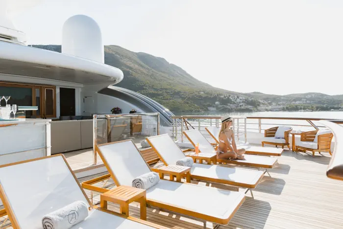 Sun loungers on a superyacht sundeck with mountain views