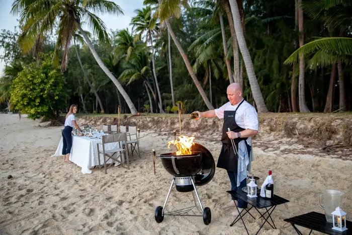Crew hosting a private beach barbecue under palm trees