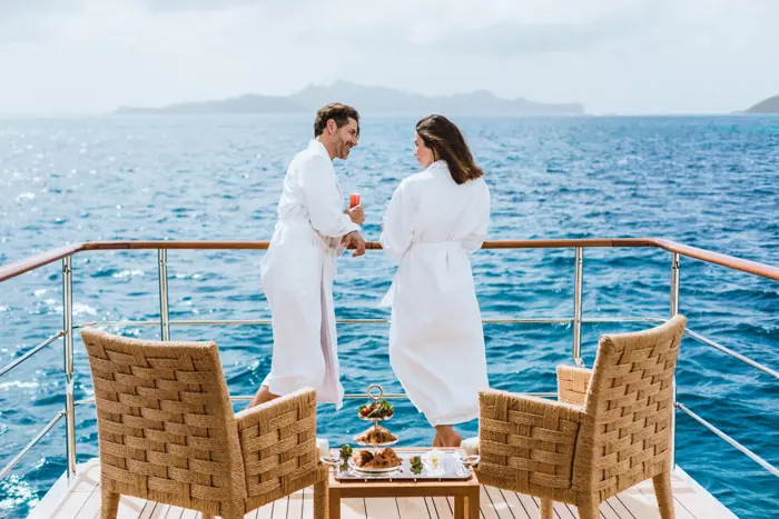 Couple in robes with morning tea on a private superyacht terrace