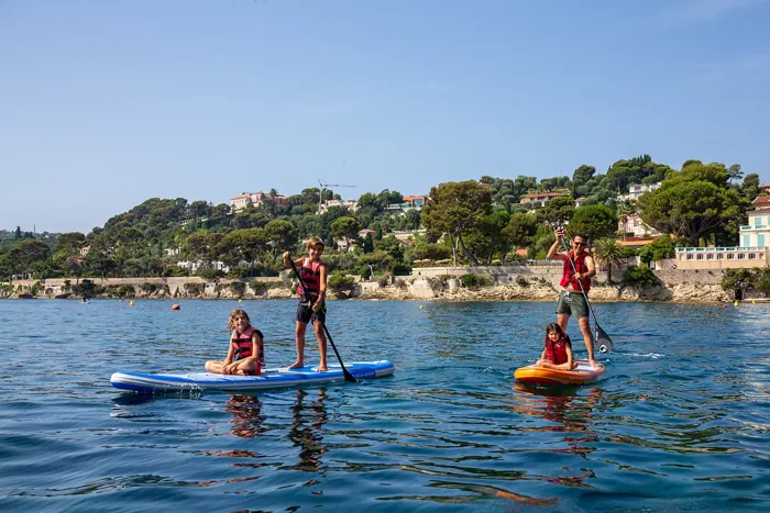 Family paddleboarding along the coast near their yacht