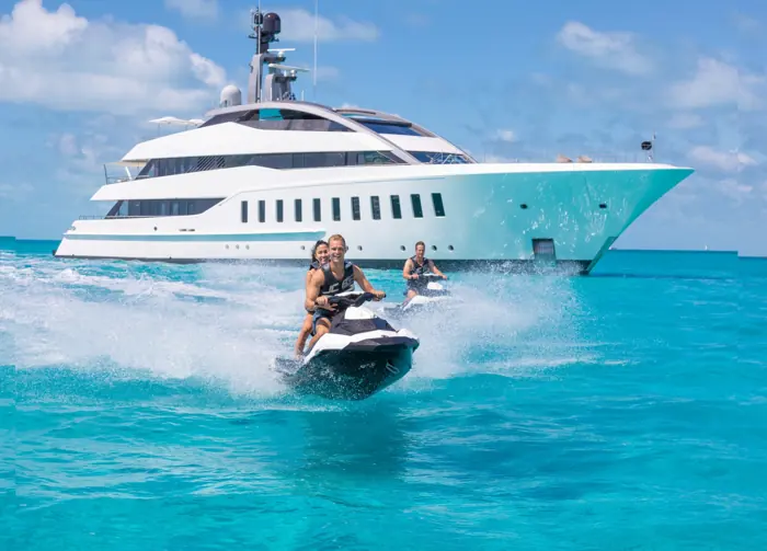 Jet ski riding past a superyacht in turquoise water
