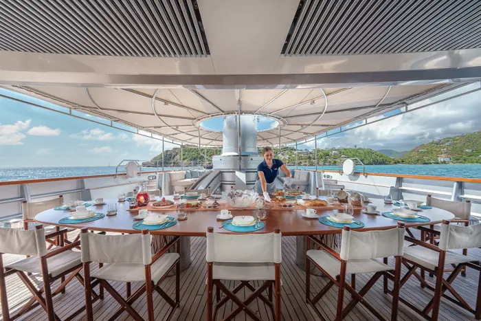 Long dining table set on the deck of a sailing superyacht